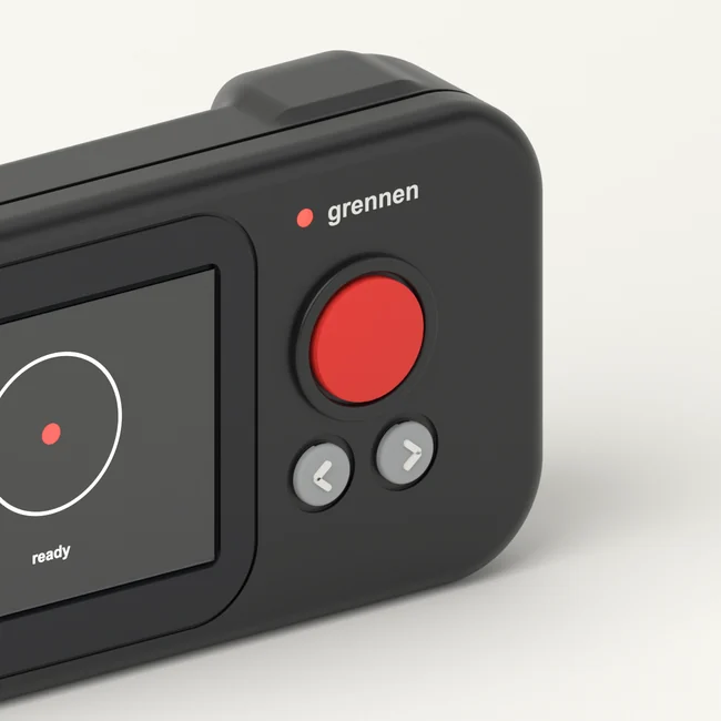 Close-up of R1 at an angle: the red button, two small keys, the grennen mark, the seam around the body and the raised grip